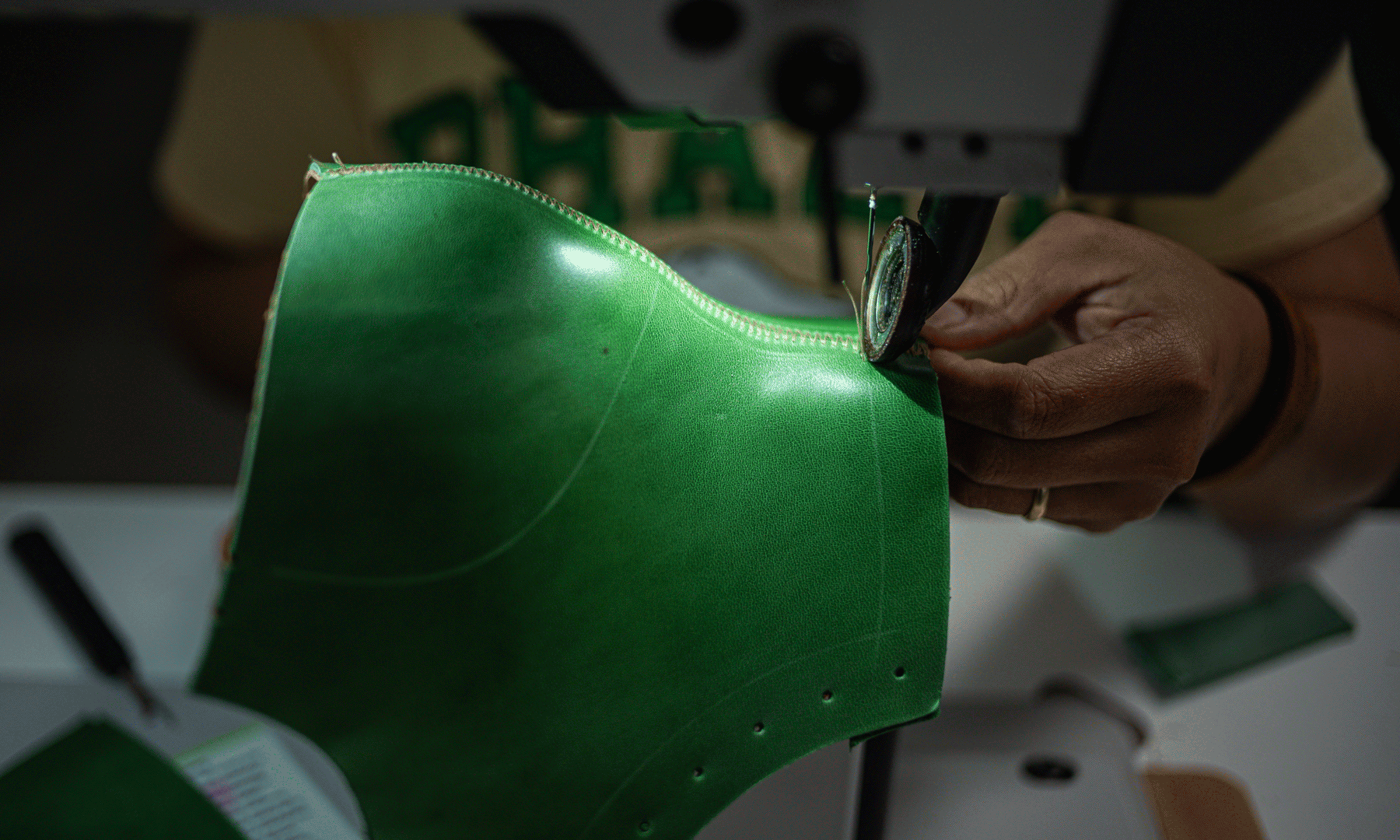 animated image of sewer sewing green horse leather boot