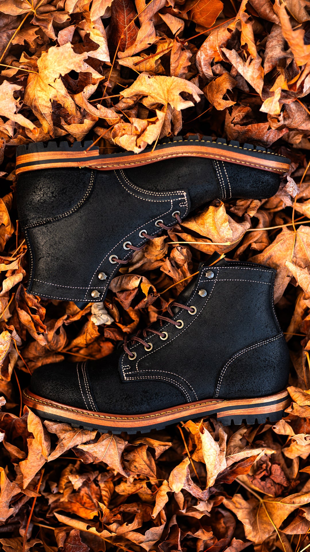 pair of black oiled rough out boots laying on fallen leaves