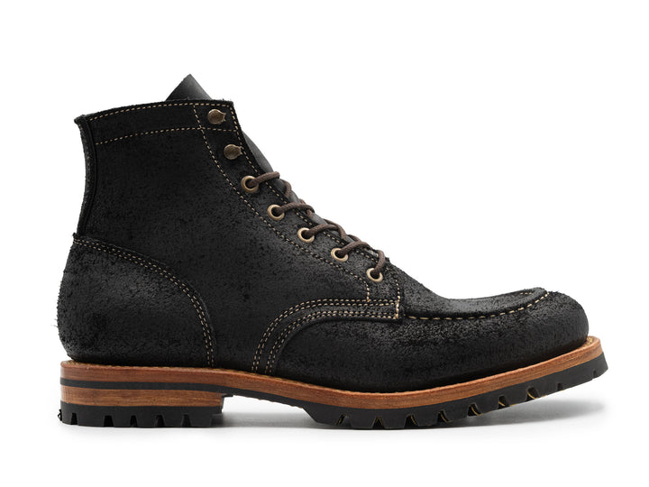 side view of black moc toe boots on white background