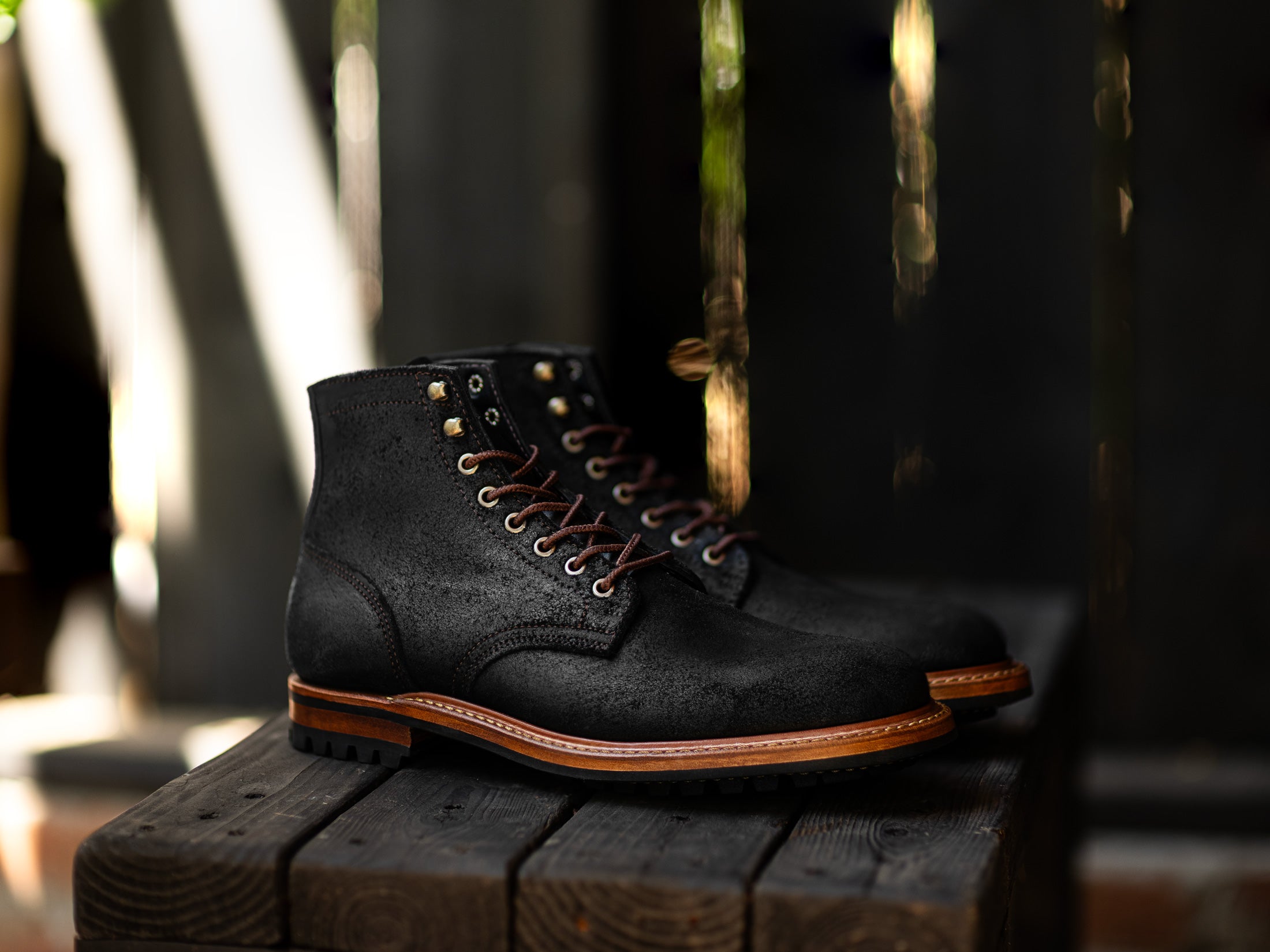 black textured boot on black wood with out of focus streaky background
