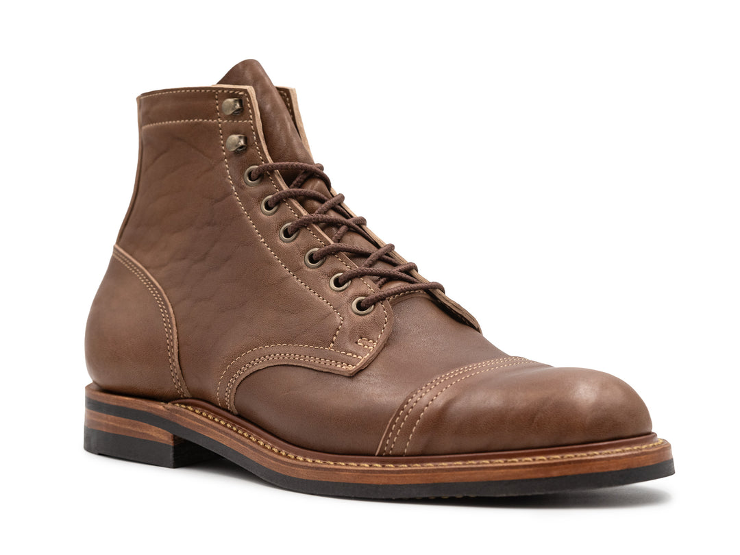 three-quarter side view of light brown leather boot on white background