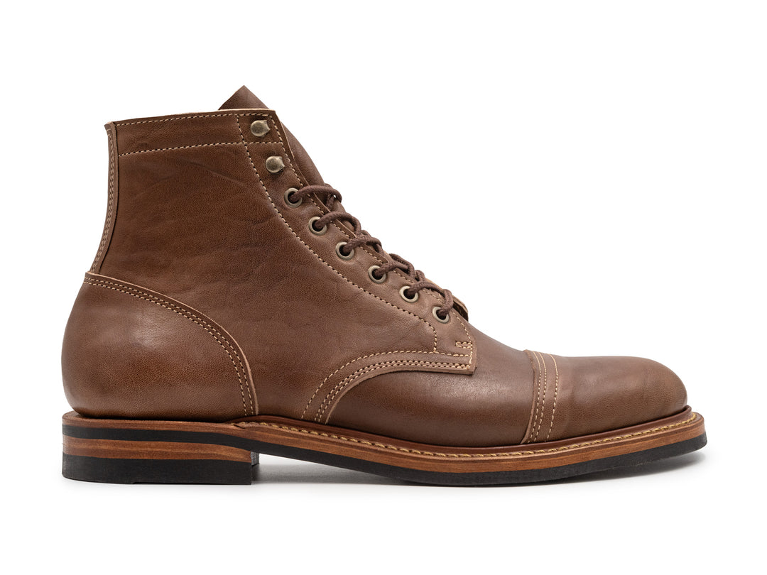 side view of light brown leather boot on white background