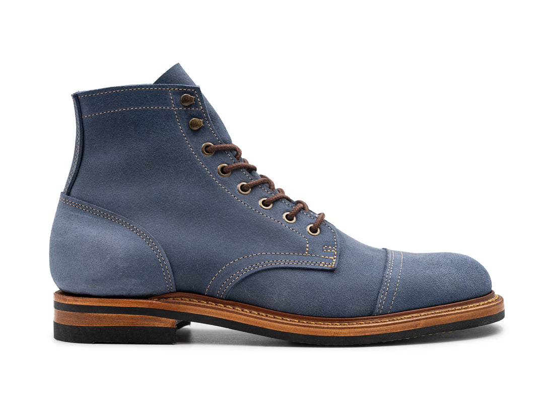 side view of blue waxy commander leather boot on white background
