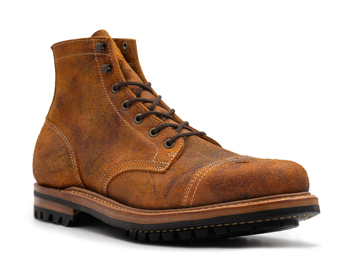 3-quarter view of single textured orange leather boot with black outsole on white background