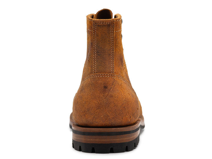 rear view of single textured orange leather boot with black outsole on white background
