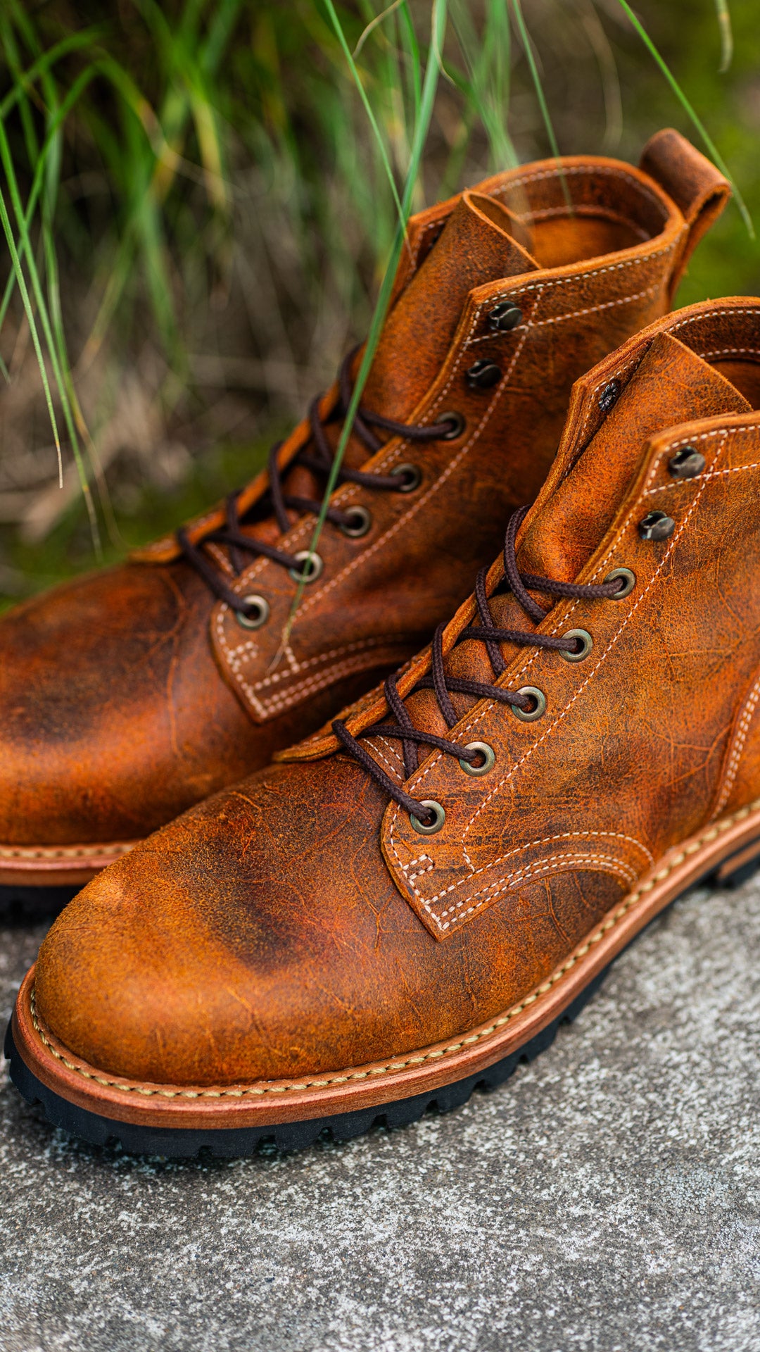 angled pair of orange textured boots with out of focus greenery behind