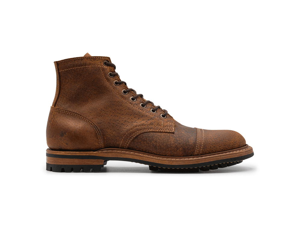 animation of 360° rotating view of textured brown leather cap toe boot on white background