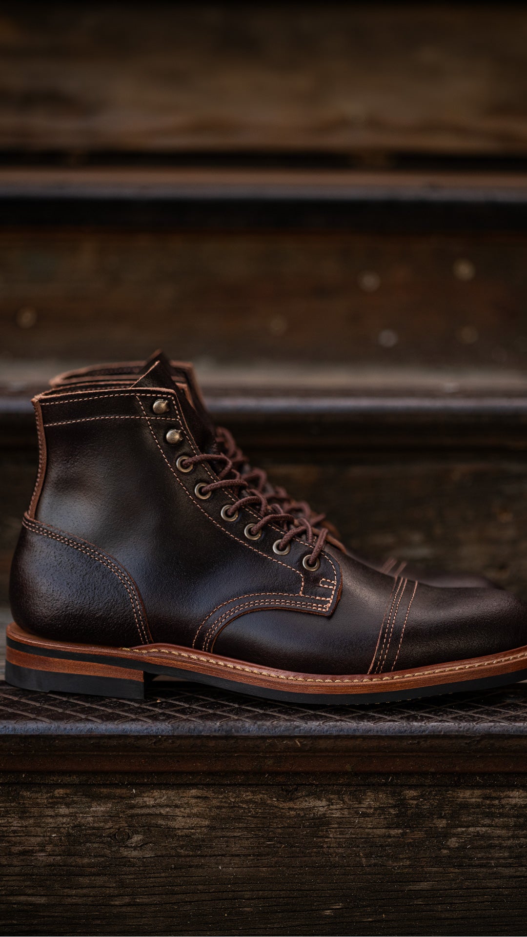 pair of brown waxed flesh boots sitting on wood and metal steps