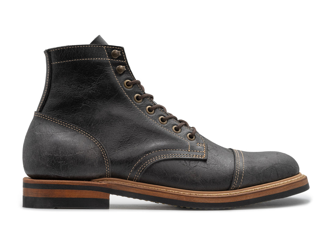 side view of gray textured leather boot on white background