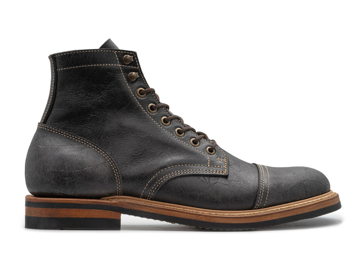 side view of gray textured leather boot on white background