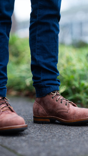 man in Italian blue pants and truman boots salmon rambler leather outside greenery