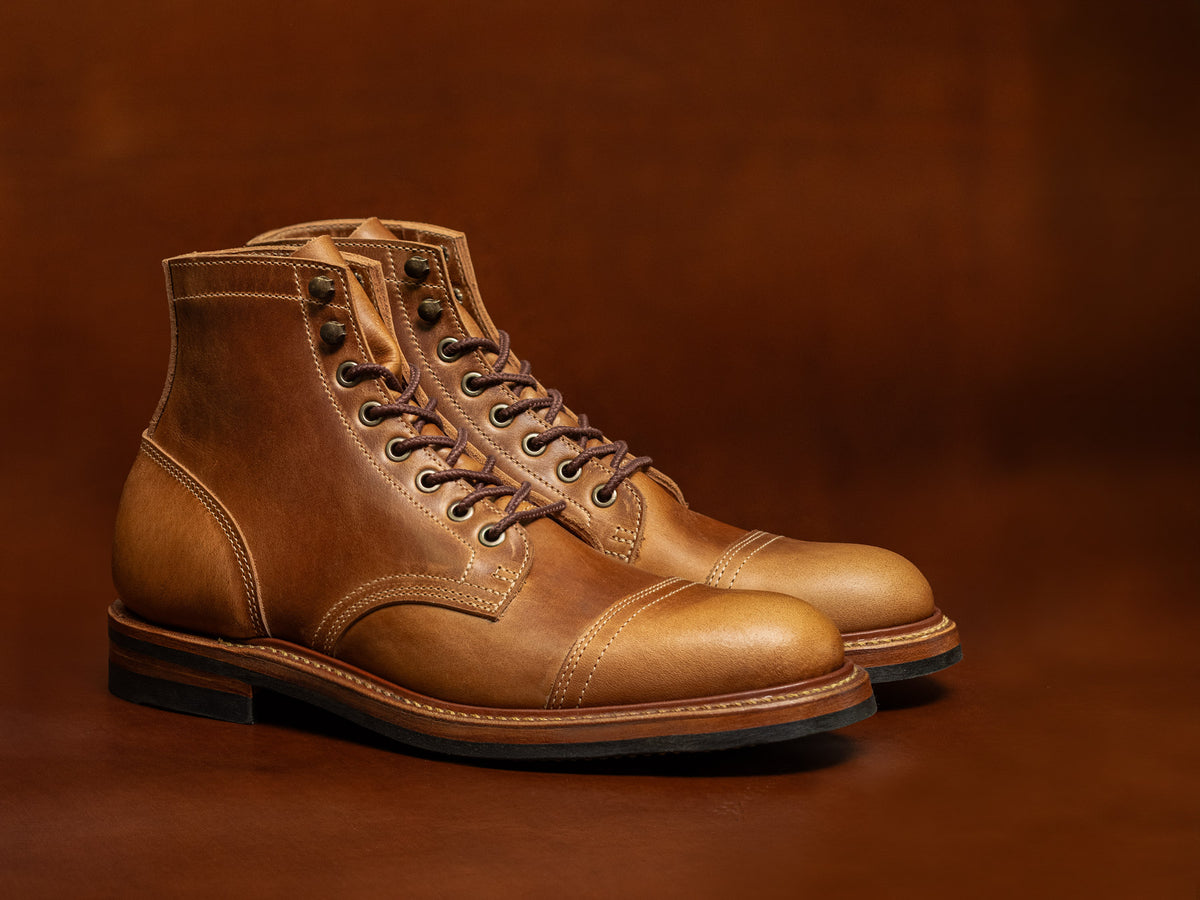 pair of tan smooth leather boots on caramel tan background