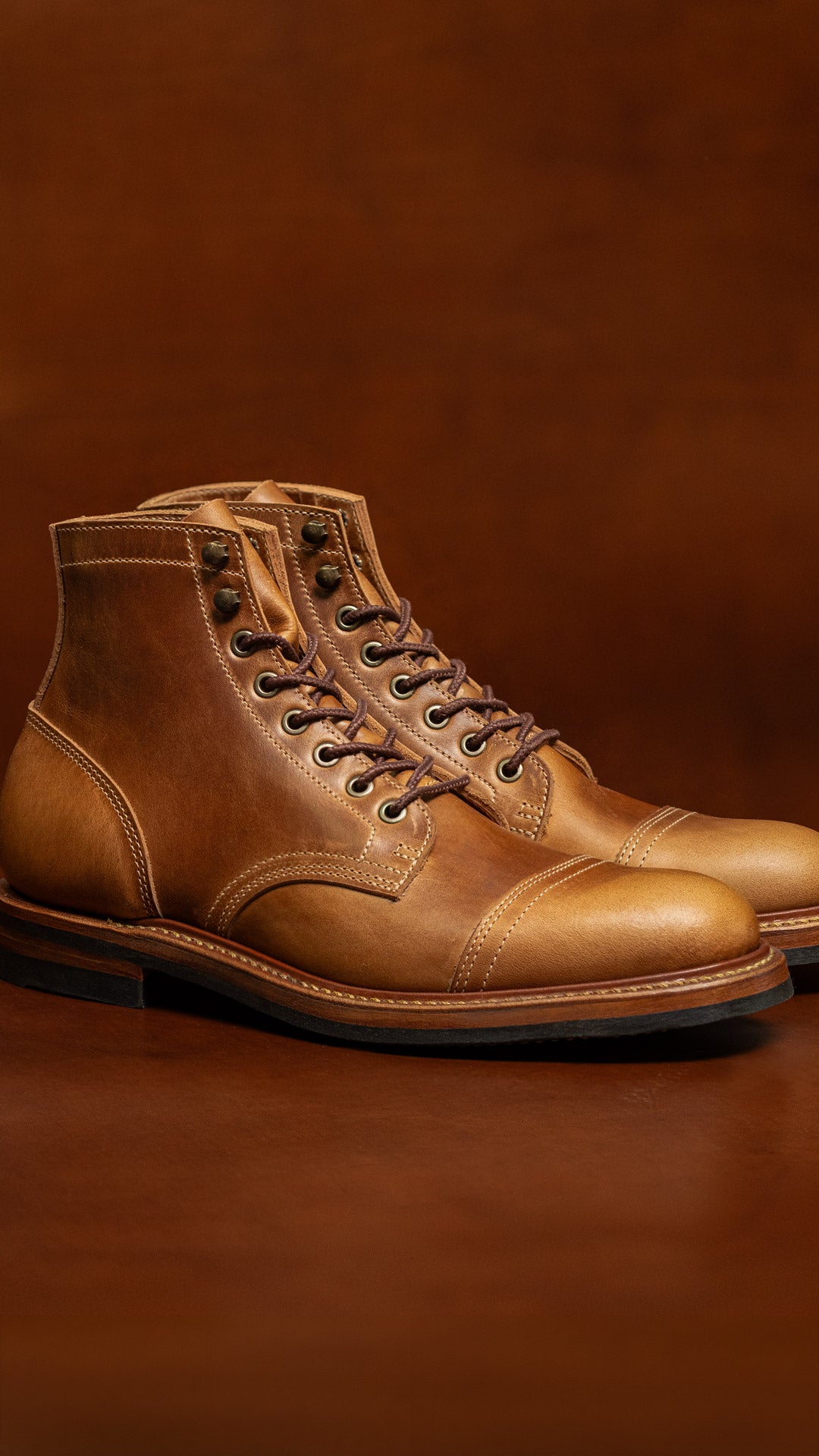 pair of tan smooth leather boots on caramel tan background