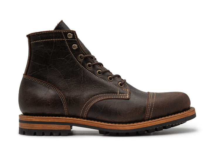 side view of brown textured leather boot on white background