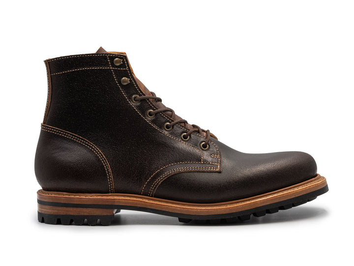 side view of brown waxed leather boot on white background