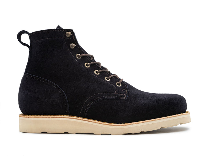 side view of dark blue suede leather boot on white wedge sole on white background