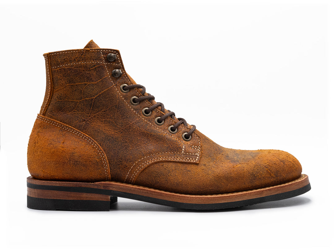 side view of textured orange leather boot on white background