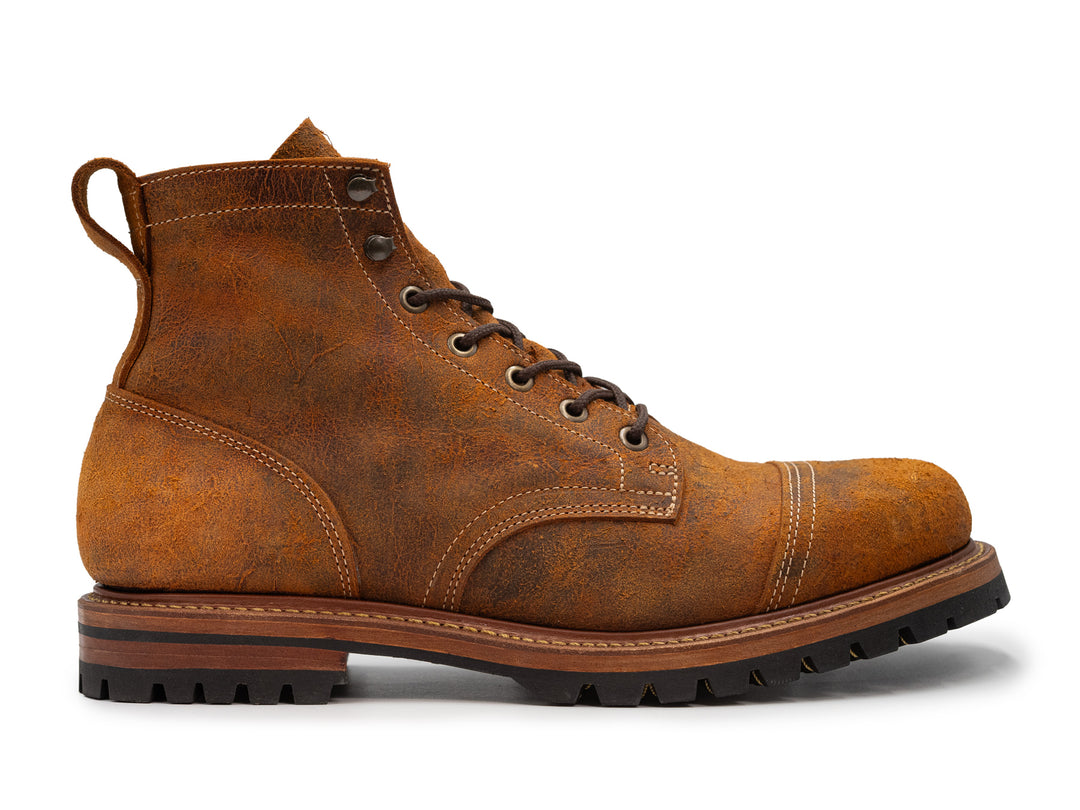 side view of orange textured leather boot on white background