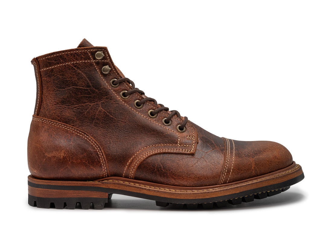 side view of brown textured boot on white background