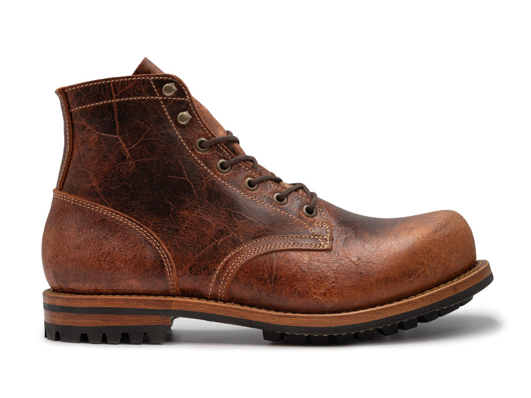 side view of brown textured leather boot on white background