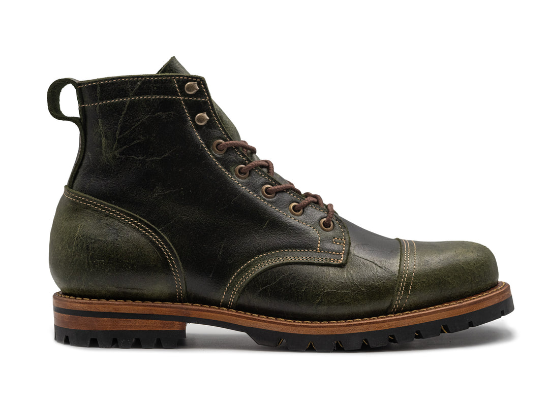 textured green leather boot on white background