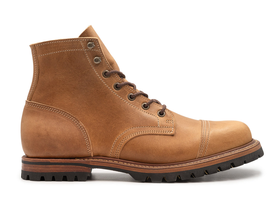 side view of tan leather boot on white background