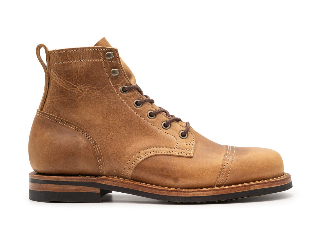 side view of tan leather boot on white background
