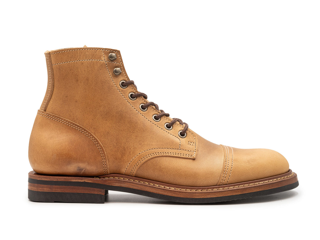 side view of tan leather boot on white background