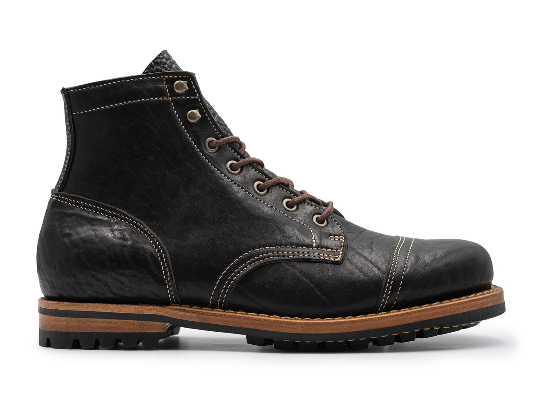 side view of black leather boot on white background