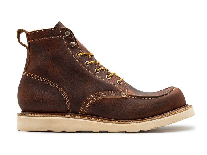 side view of rustic brown leather moc toe boot on white background