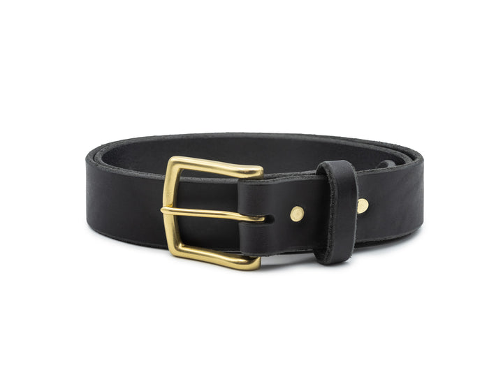 black veg tan leather belt with brass buckle coiled on white background